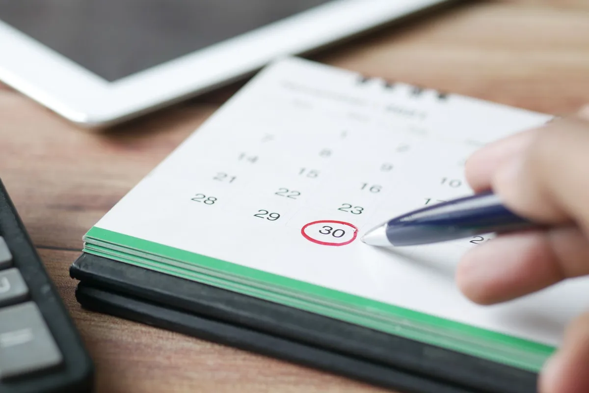 Hand mit Kugelschreiber kreist auf einem Tischkalender die 30 ein: die 30-Tage-Frist bis zum Widerruf der Domain bei nic.at