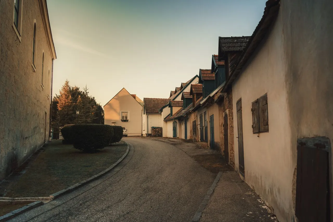 Menschenleere Dorfstraße mit alten Kellerhäusern und Schindeldächern im Abendlicht, wie sie im Burgenland und im östlichen Niederösterreich typisch ist