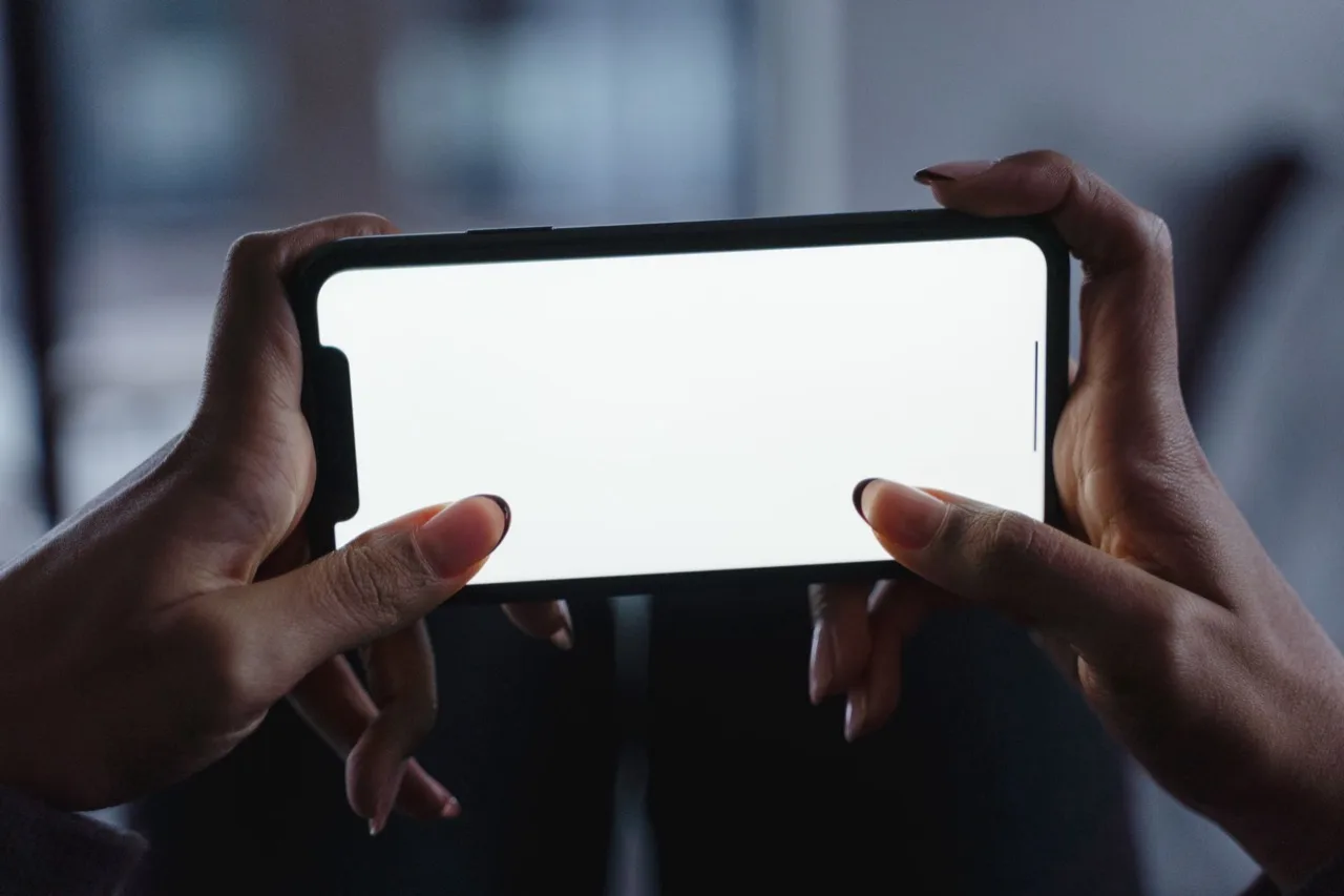 Zwei Hände halten ein Smartphone im Querformat mit leerem Bildschirm
