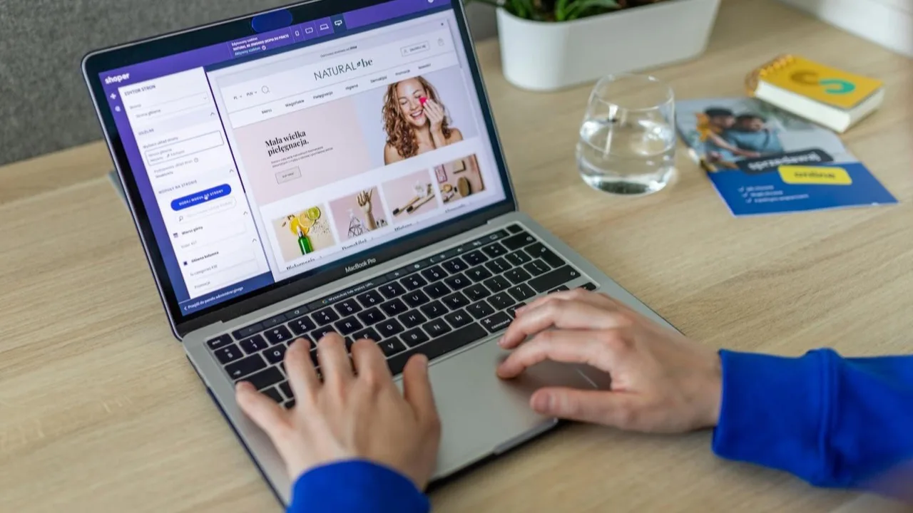 Laptop mit geöffnetem Website-Baukasten im Browser, eine Person bearbeitet die Startseite per Drag-and-drop
