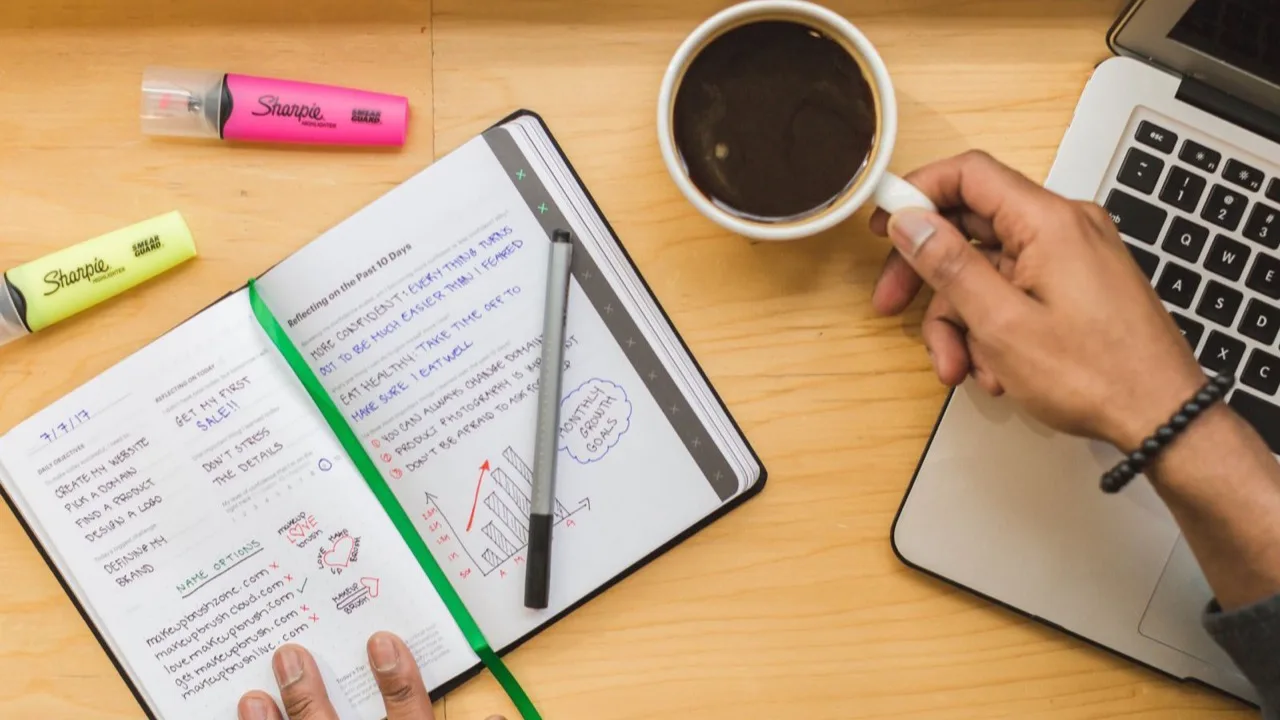 Schreibtisch mit handgeschriebenem Website-Plan, Stiften und Laptop als Sinnbild für die Entscheidung selbst bauen oder erstellen lassen