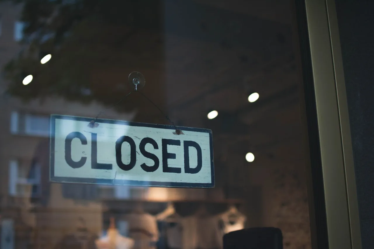 Geschlossen-Schild hinter der Glasscheibe eines abgedunkelten Ladenlokals